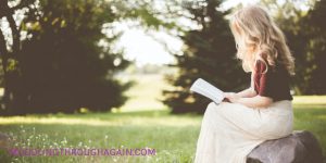 Blonde woman reading Bible outdoors
